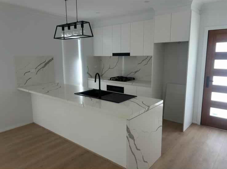 White stone kitchen with black tapware in a newly built home